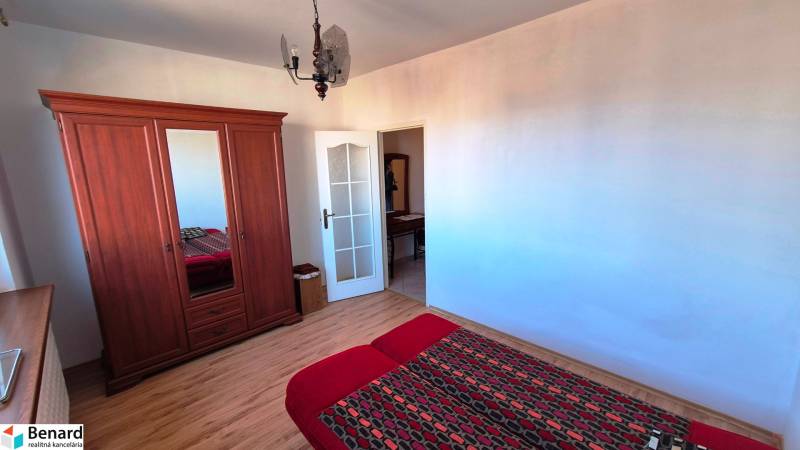 Bedroom in a 2-room apartment with a wooden decor floor, wardrobe, and bed.
