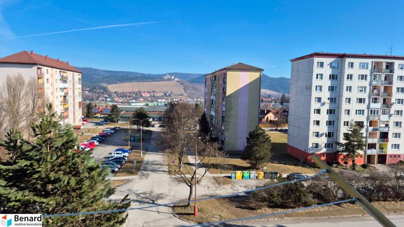Housing estate in Stará Ľubovňa with a parking lot and a view of the hills.