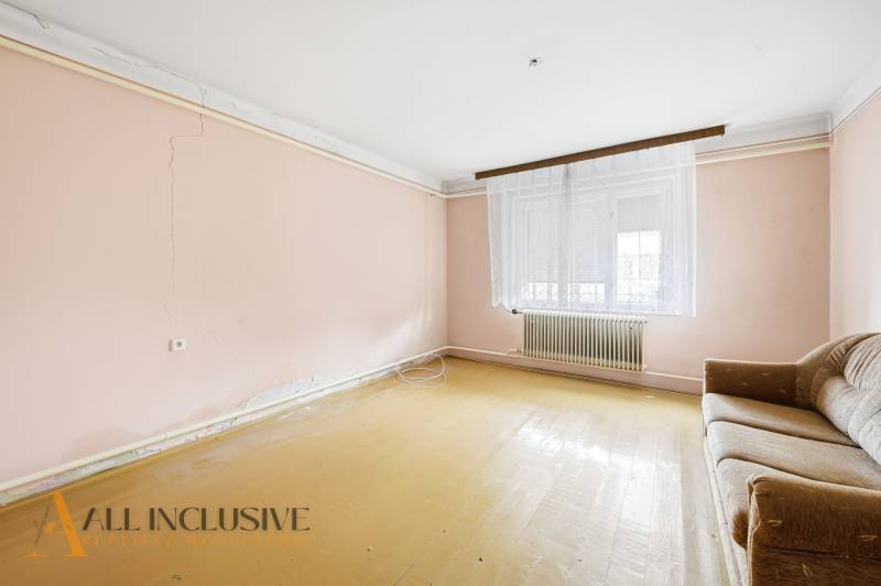 Living room with simple furniture and light pink walls in a family house.
