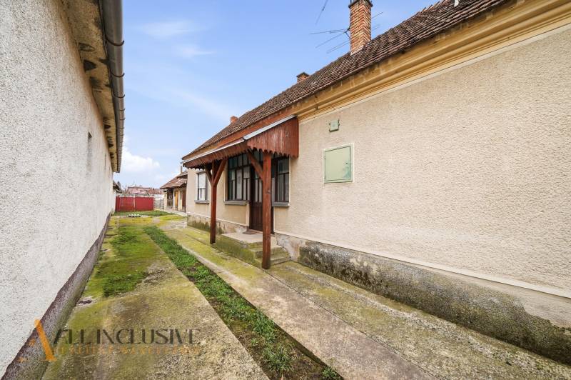 A family house in Topoľníky with a well-maintained facade, a veranda, and a concrete walkway.
