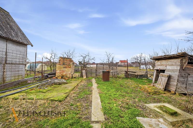 Garden in a family house in Topoľníky with old buildings and fencing.