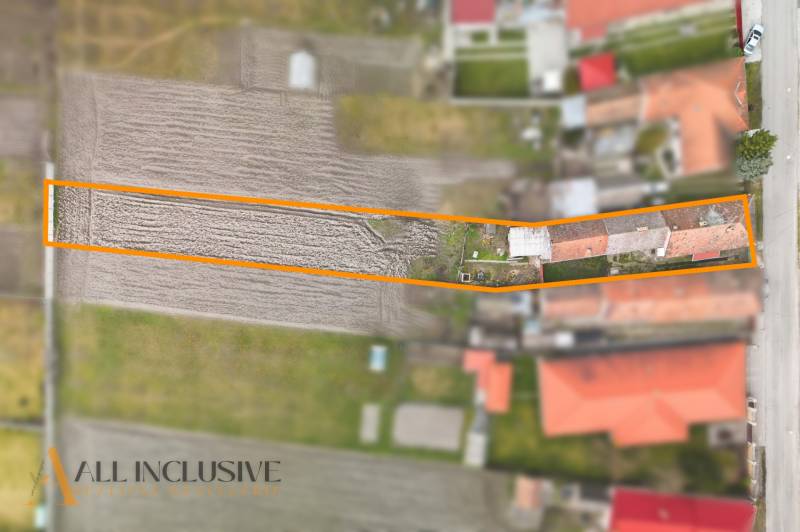 A family house in Topoľníky with a garden in the frame, visible agricultural field and buildings.