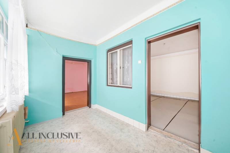 A room in a family house with colorful walls, laminate flooring, and a large window.