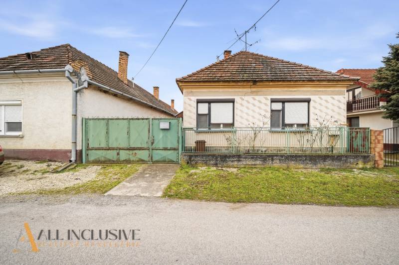 A family house in Topoľníky with a green gate and metal fence, sloped roof.