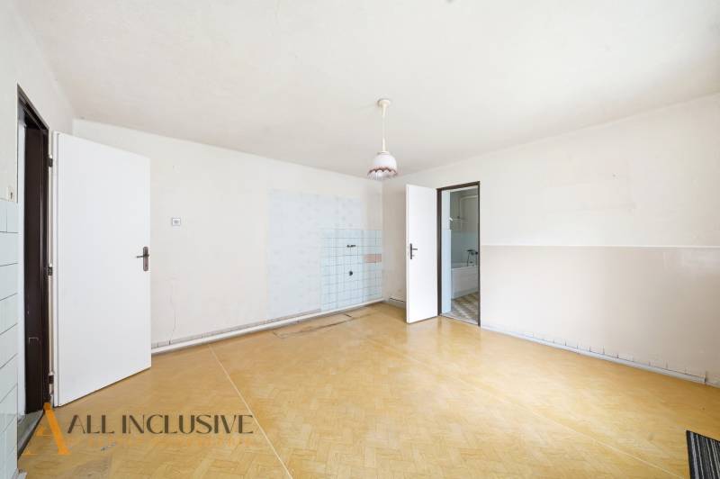 A spacious room in a family house with a wooden decor floor and simple lighting.