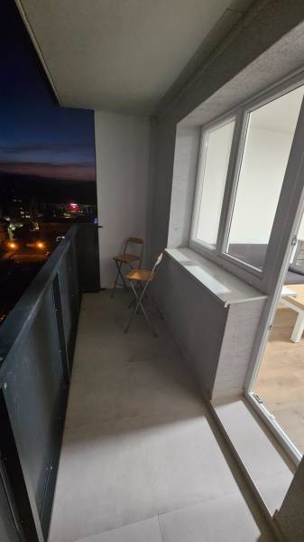 A balcony of a studio apartment in Pod Hájom, Dubnica nad Váhom, with a folding chair and a tiled floor.