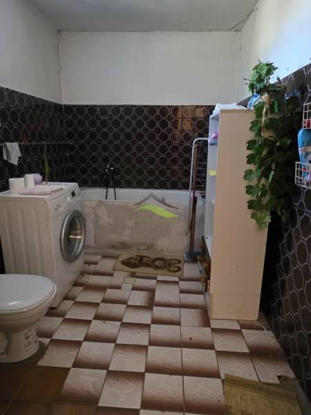 A bathroom in a family house with a washing machine and decorative wall tiles.