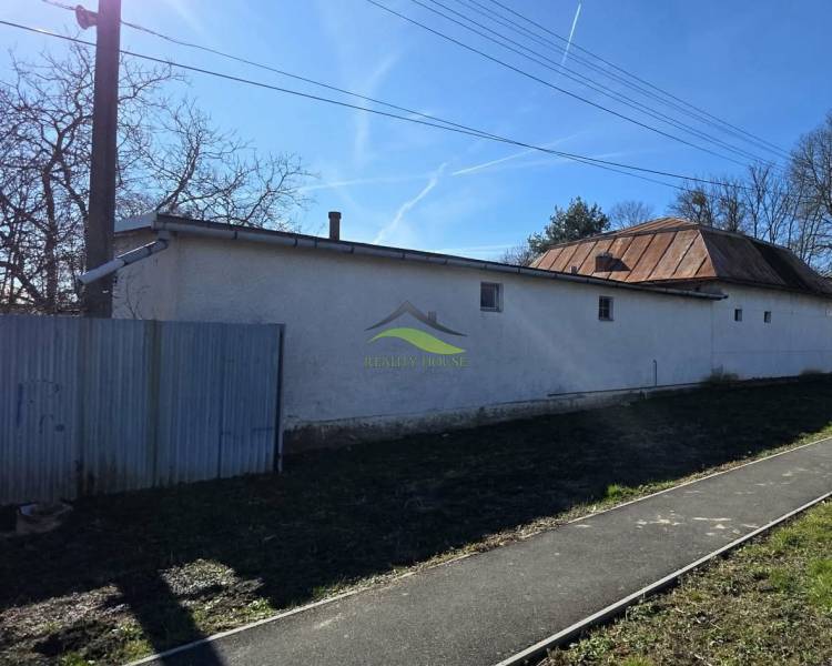 Pavlovce nad Uhom, a family house with a metal roof and fencing, next to a narrower road.