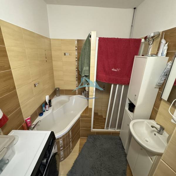 Bathroom in a 3-room apartment with a bathtub, sink, and washing machine; storage space.