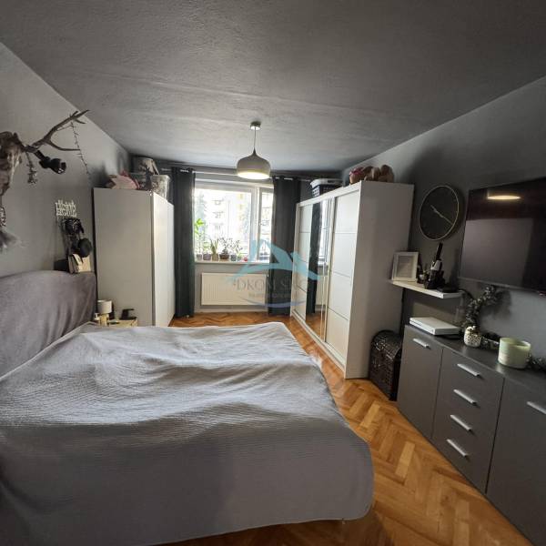 A bedroom in a 3-room apartment with a wardrobe, bed, and wooden decor flooring.