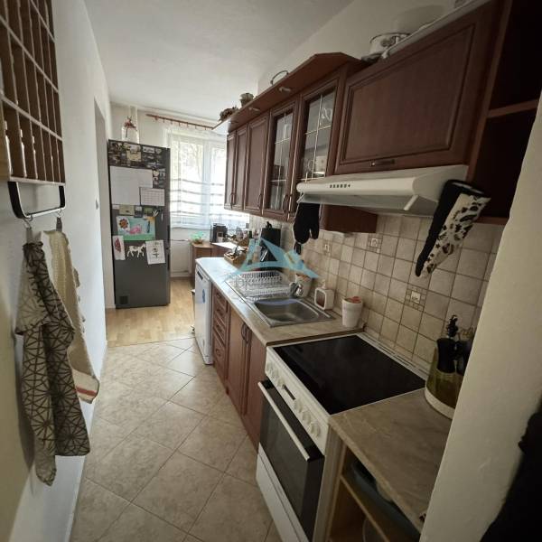 A narrow kitchen with a kitchen unit and a wooden decor floor in a 3-room apartment.