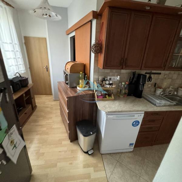 A kitchen with a wooden floor decor in a 3-room apartment with wooden cabinets and appliances.
