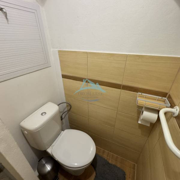 A bathroom in a 3-room apartment with a toilet and tiles with a wooden decor.