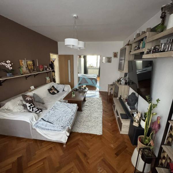 Living room with a sofa, table, and wooden decor flooring in a 3-room apartment.