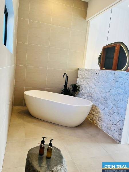 A bathroom in a family house with a freestanding bathtub and stone wall cladding.