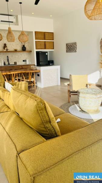 The interior of a family house with a sofa, kitchen, rattan chairs, and accessories made from natural materials.