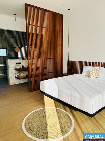 A bedroom in a family house with a wood-patterned floor, a wooden partition, and a circular rug.