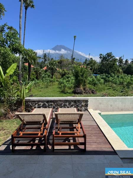 A swimming pool at a family house in Amed with a view of the mountains and greenery.
