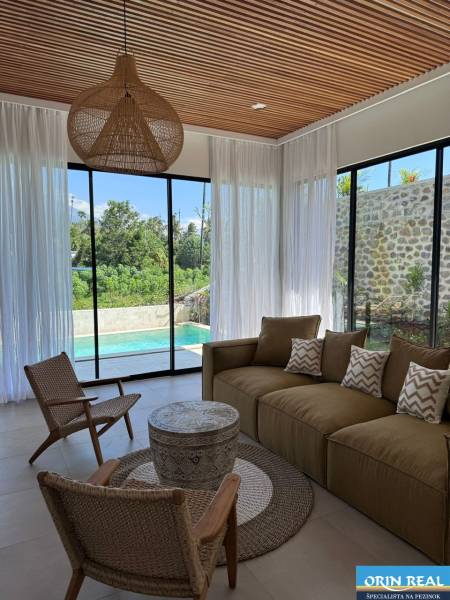 Interior of a family house with a view of the pool. Comfortable couch, armchairs, and decorative elements.