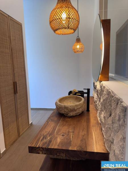 Interior of a family house with a stone sink, wooden countertop, and hanging lamps.