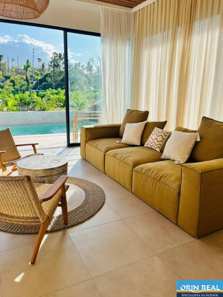 Living room of a family house with a large window, view of the garden and pool.