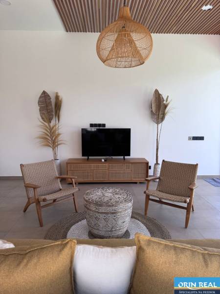 Living room of a family house with wooden decor, television, and wicker furniture.
