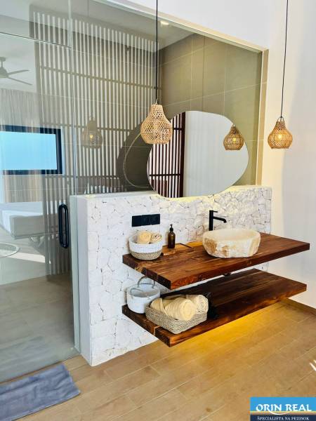 Bathroom in a family house with a sink on a wooden shelf and a floor with a wood decor.