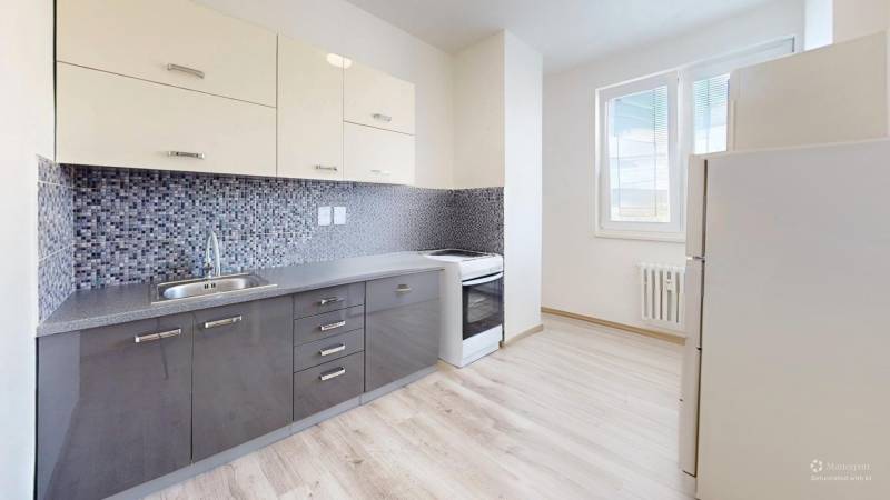 Kitchen in a 2-room apartment with a modern kitchen unit and flooring with a wood decor.