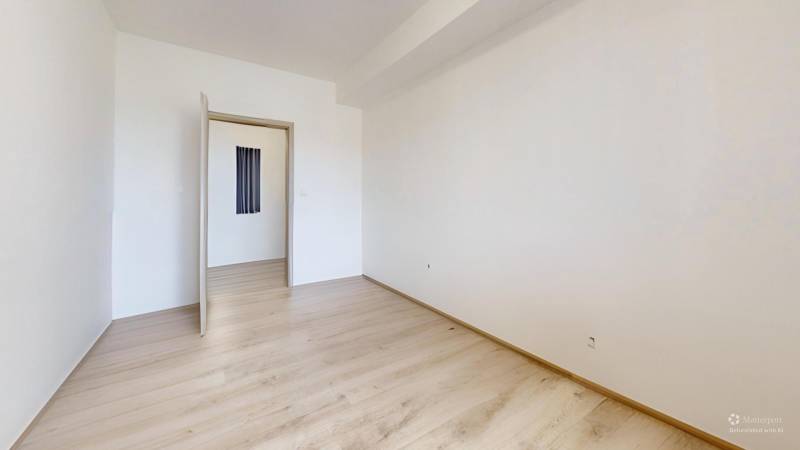 A room with white walls and a wooden decor floor in a 2-room apartment.