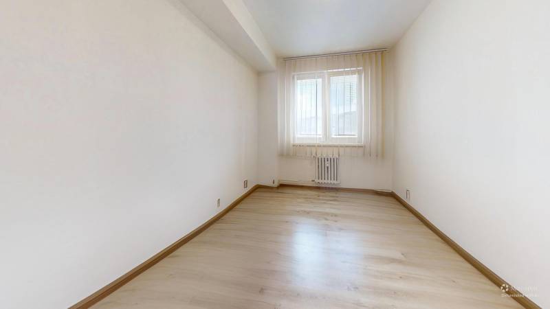 A bright room with a window and a wooden decor floor in a 2-room apartment.