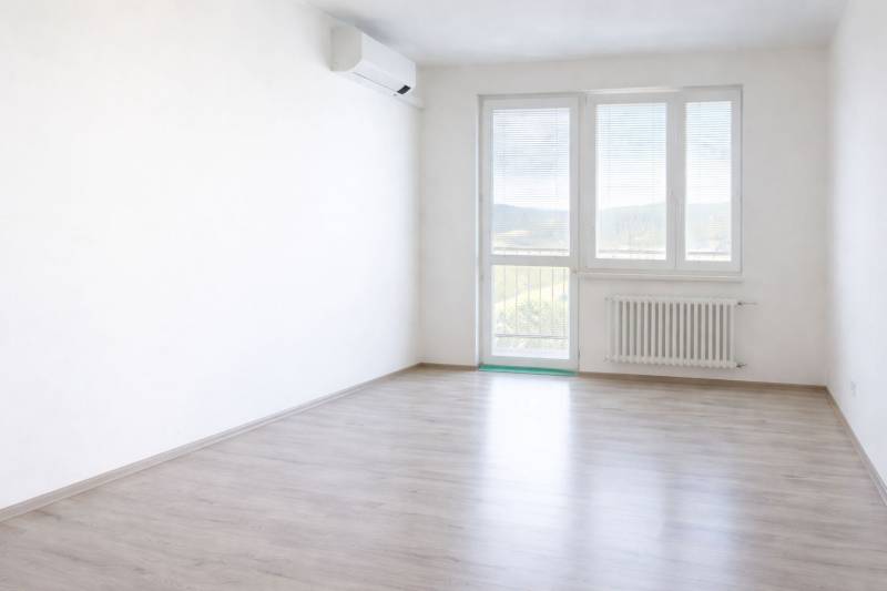 A bright space of a 2-room apartment with a wooden decor floor and air conditioning.