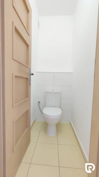 Bathroom with beige tiles in a 2-room apartment, toilet and white walls.