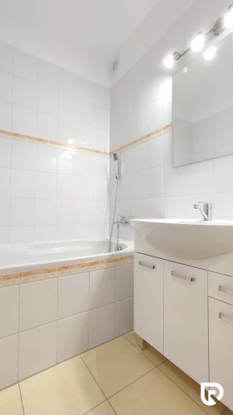 Bathroom in a 2-room apartment with white tiles and a bathtub.