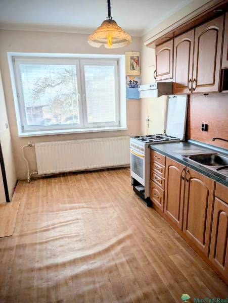 A kitchen in a family house with a wooden decor floor and a pendant light.