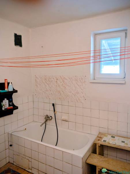 A bathroom in a family house with a bathtub, a shelf, and white tiles.
