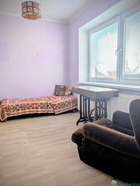 A room in a family house with a sofa bed and an armchair, flooring with a wooden decor.