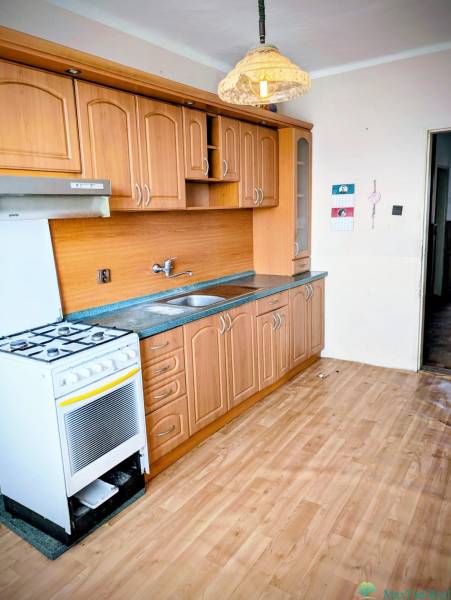 A kitchen in a family house with a classic kitchen unit and a floor with a wooden decor.
