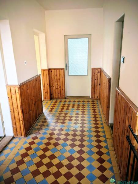 A hallway in a family house with a tiled floor and wooden paneling on the walls.