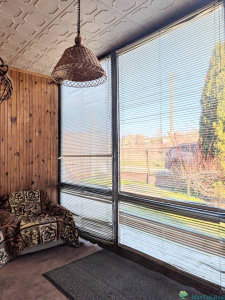 Family house with a rattan lamp, an armchair with a blanket, and windows with blinds.