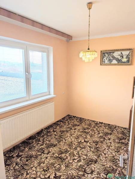 In the family house, there is a room with a carpeted floor, a hanging chandelier, and a painting.