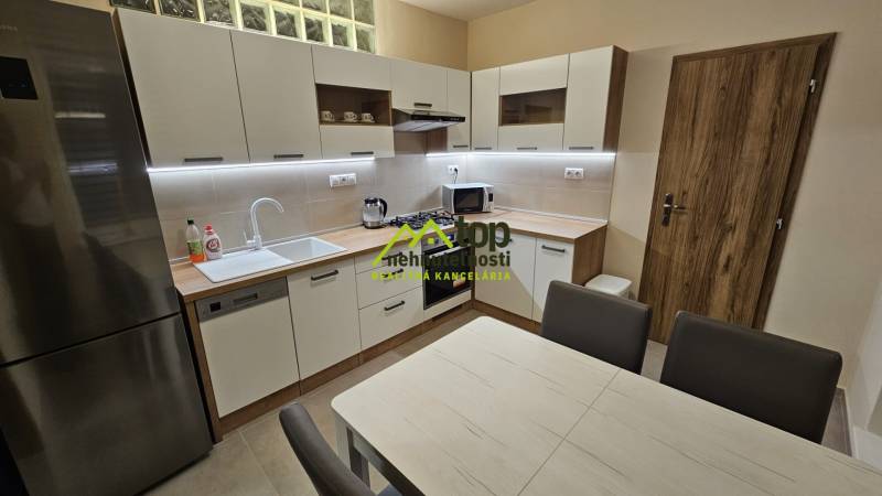 A kitchen in a 2-room apartment with wooden decor, modern equipment, and a dining table.