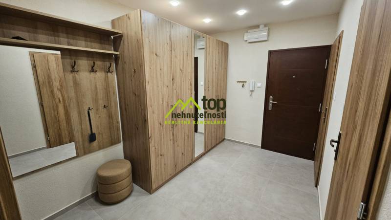 A hallway in a 2-room apartment with furniture featuring a wood decor and a built-in mirror.