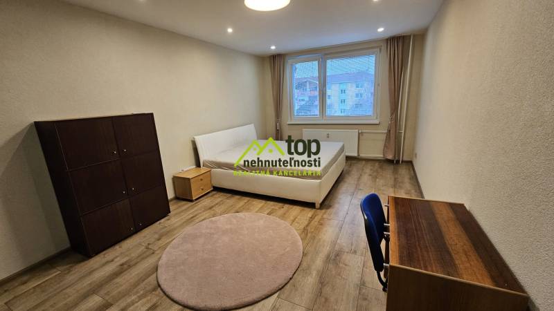 A bright room in a 2-room apartment with a bed and furniture, floor with wood decor.