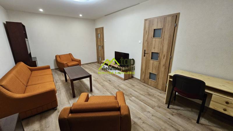 Living room in a two-room apartment with orange furniture and a wooden decor floor.