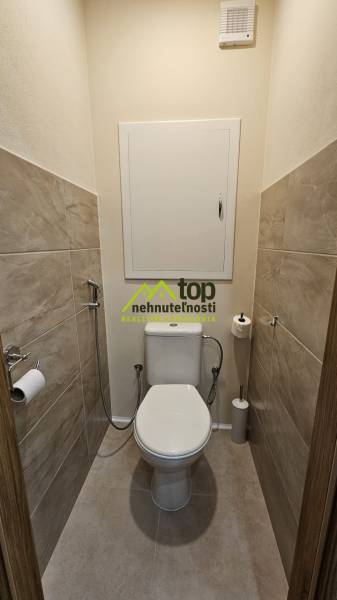 A toilet with tiles and a ceramic toilet in a 2-room apartment.
