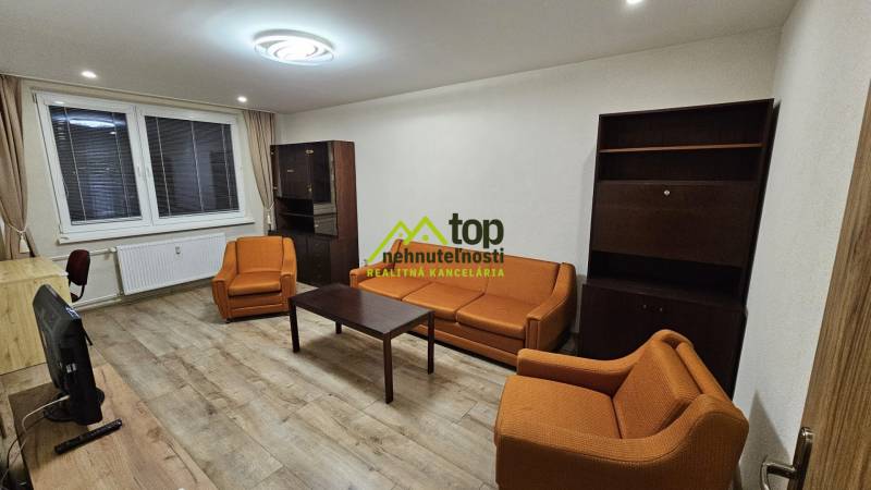 Living room in a two-room apartment with orange sofas and a floor with a wooden decor.