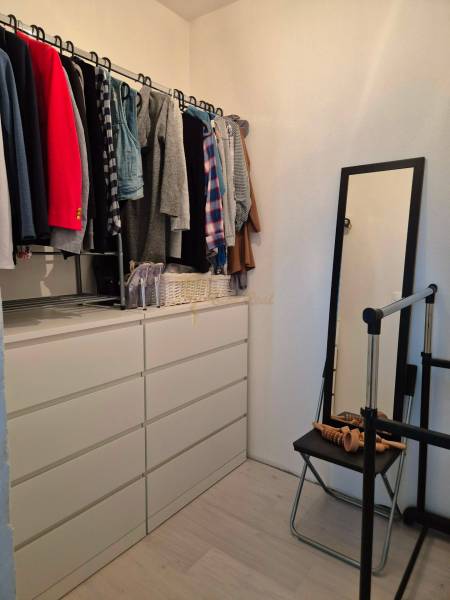 A wardrobe in a 3-room apartment with hangers and a dresser, floor with a wooden decor.