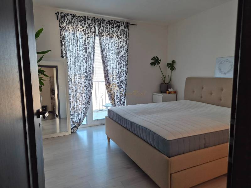 A bedroom with a large bed, plants, a mirror, and curtains in a 3-room apartment.