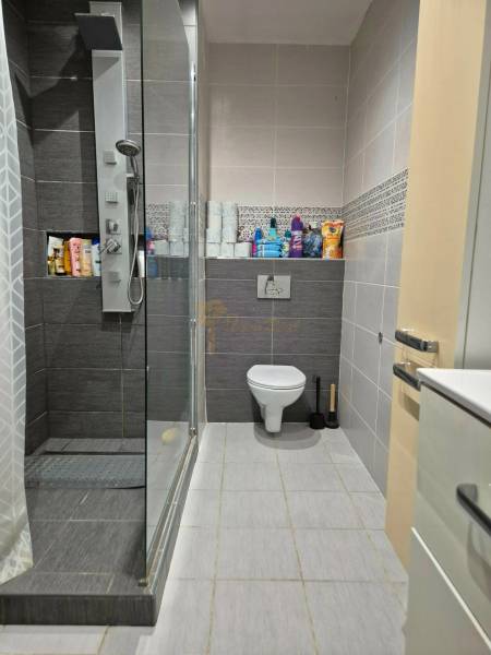 Bathroom in a 3-room apartment with a shower and toilet, with storage space for cosmetics.