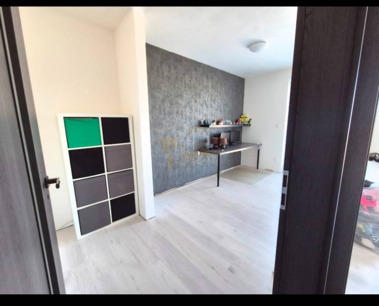 A room in a 3-room apartment with a wooden decor floor and a decorative wall.